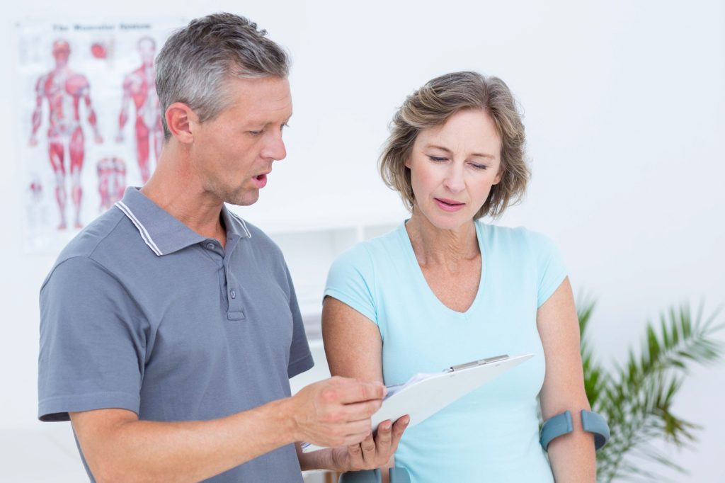 Woman using crutch and talking with her doctor